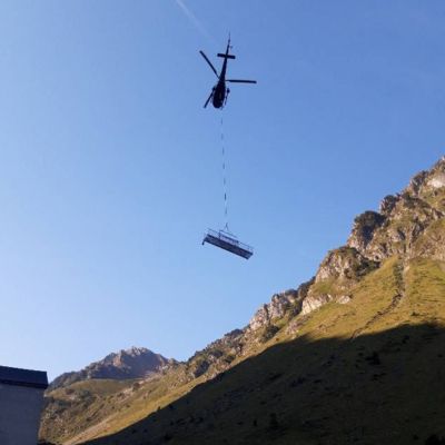 photo d'un hélicoptère amenant une pièce pour la construction du refuge de montagne d'Aygues-Cluses - Refuge construit par l'architecte Nathalie Ott